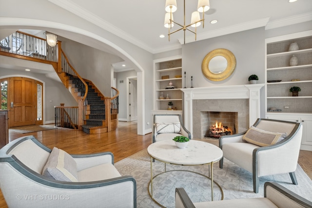 living room featuring a high end fireplace, an inviting chandelier, light hardwood / wood-style flooring, and ornamental molding