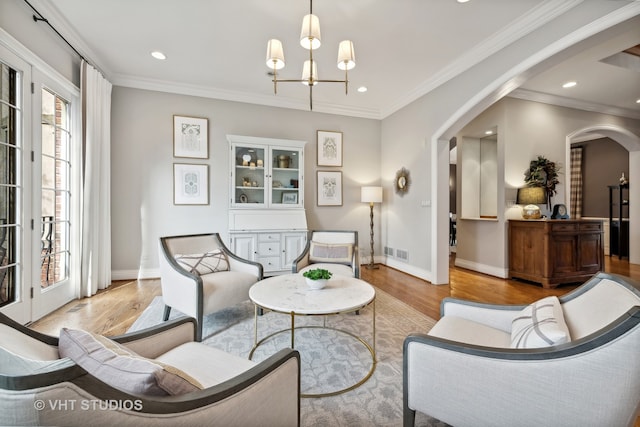 living area with an inviting chandelier, light hardwood / wood-style flooring, and ornamental molding