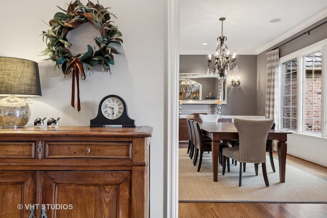 dining space with an inviting chandelier, crown molding, and light hardwood / wood-style flooring