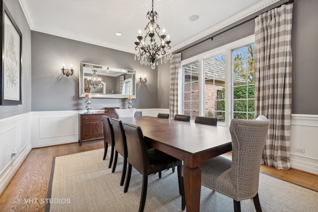 dining space with crown molding, light hardwood / wood-style flooring, and a notable chandelier