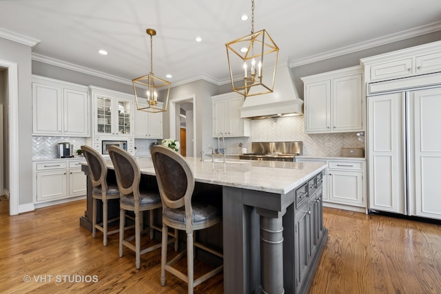 kitchen featuring white cabinets, paneled built in fridge, hanging light fixtures, and hardwood / wood-style flooring