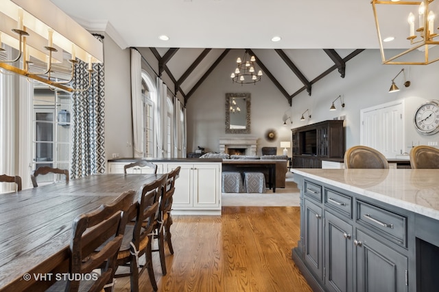 kitchen with beam ceiling, gray cabinetry, white cabinetry, hanging light fixtures, and light hardwood / wood-style flooring