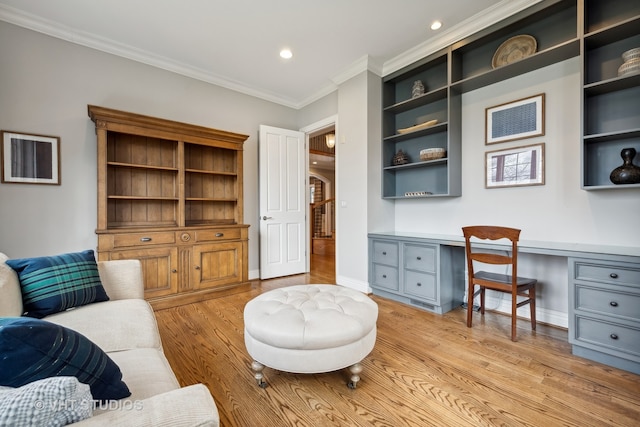 office area featuring light wood-type flooring, built in desk, and ornamental molding