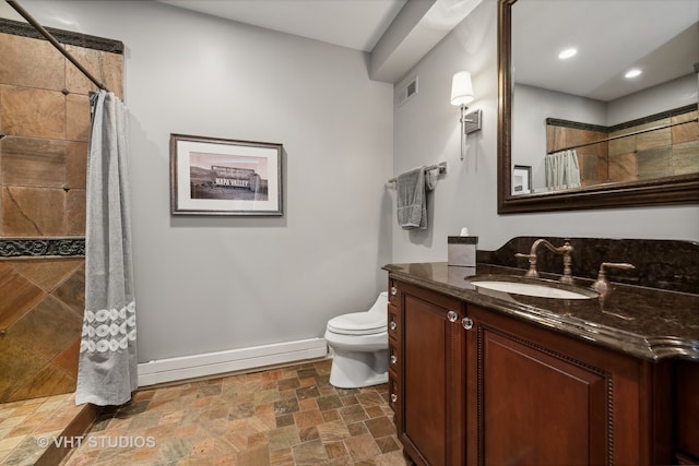 bathroom with walk in shower, vanity, and toilet