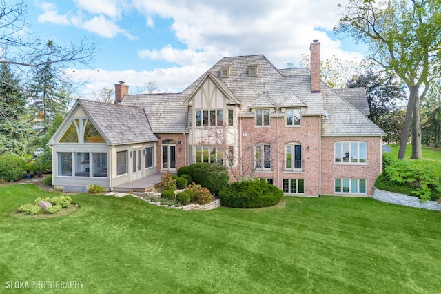 rear view of house featuring a sunroom and a lawn