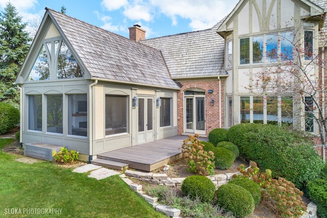 rear view of property with a lawn, a sunroom, and a deck