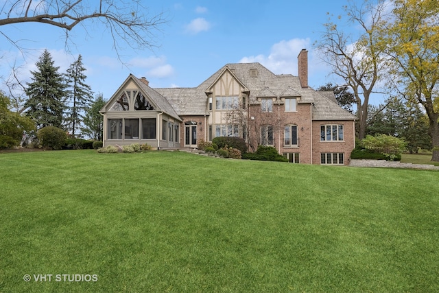 english style home featuring a front lawn and a sunroom