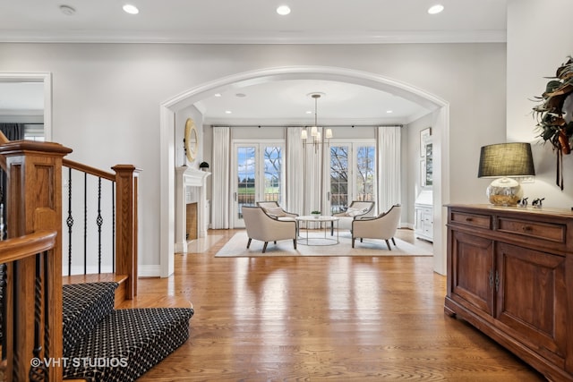 living area featuring an inviting chandelier, light hardwood / wood-style flooring, and crown molding