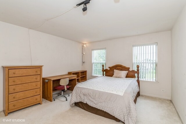 carpeted bedroom with rail lighting