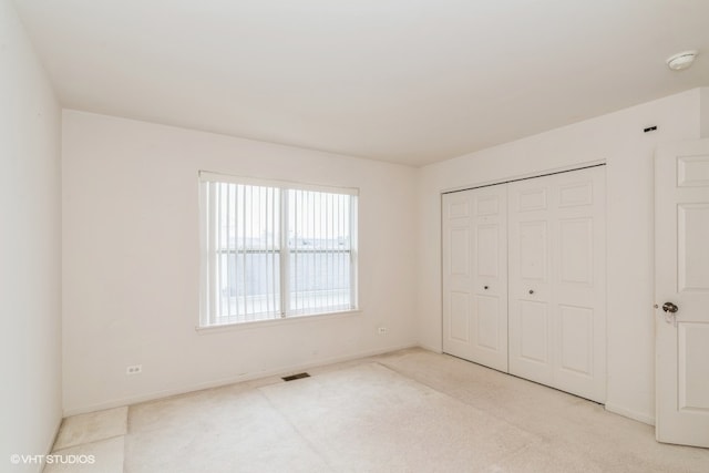 unfurnished bedroom featuring light colored carpet and a closet