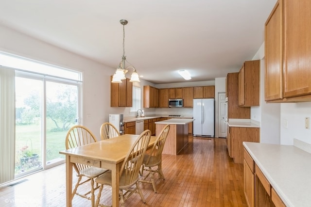 dining room with an inviting chandelier, light wood-type flooring, plenty of natural light, and sink