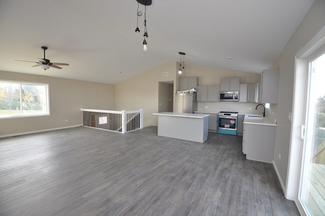 kitchen with stainless steel appliances, a kitchen island, gray cabinets, hanging light fixtures, and lofted ceiling