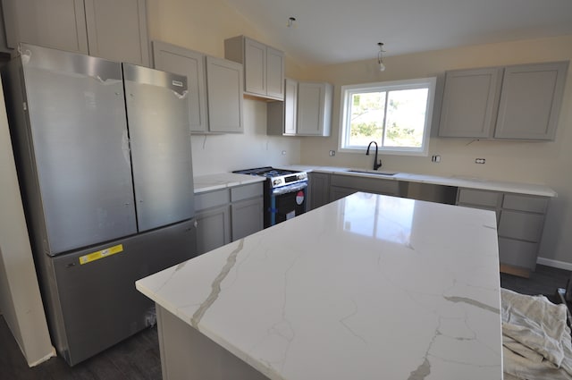 kitchen featuring light stone counters, sink, a kitchen island, and appliances with stainless steel finishes