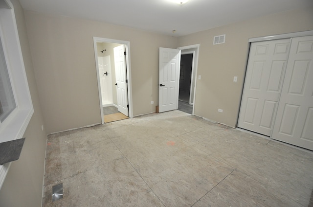 unfurnished bedroom with ensuite bath and a closet