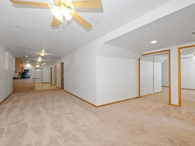 basement with light carpet, ceiling fan, and black fridge