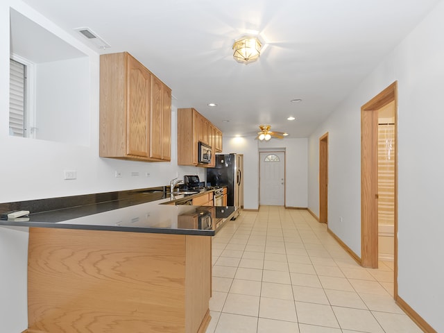 kitchen with kitchen peninsula, light tile patterned floors, stainless steel appliances, ceiling fan, and sink