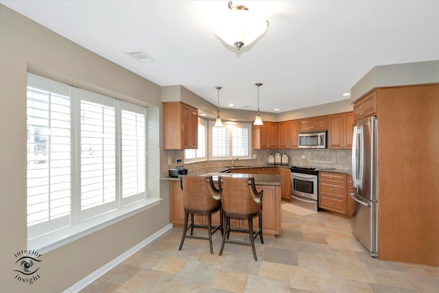 kitchen featuring visible vents, decorative backsplash, appliances with stainless steel finishes, a peninsula, and a sink