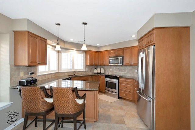 kitchen with backsplash, appliances with stainless steel finishes, a sink, a peninsula, and a kitchen breakfast bar