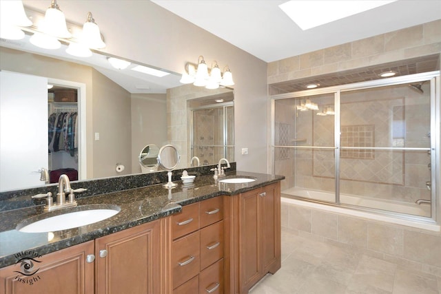 bathroom with a skylight, a walk in closet, a sink, and double vanity