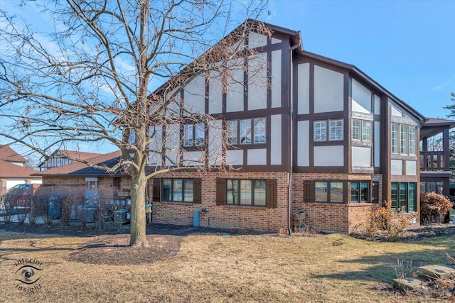 back of property with brick siding, a yard, and stucco siding