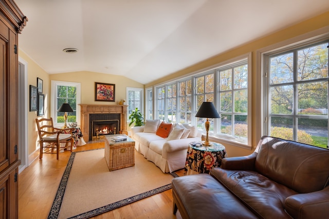 sunroom / solarium with a brick fireplace, a healthy amount of sunlight, and vaulted ceiling