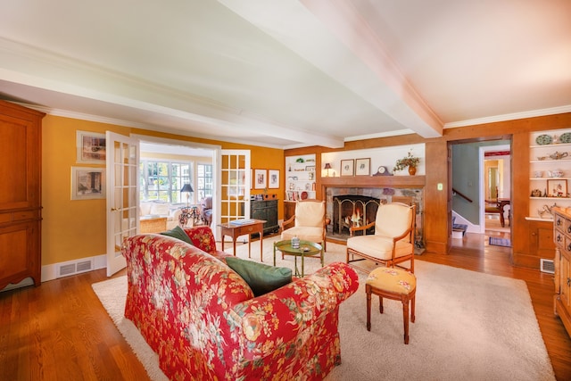 living room featuring hardwood / wood-style floors, beamed ceiling, french doors, and ornamental molding