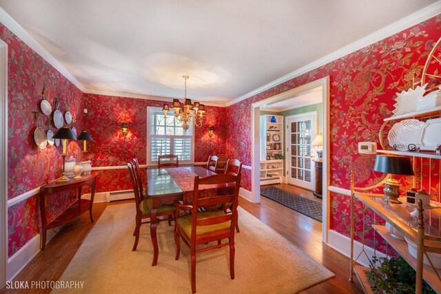 dining room featuring crown molding, wallpapered walls, an inviting chandelier, and wood finished floors