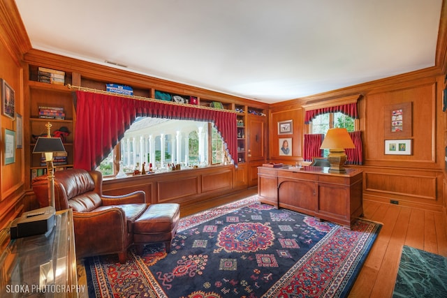 home office with plenty of natural light, wood-type flooring, built in features, and ornamental molding