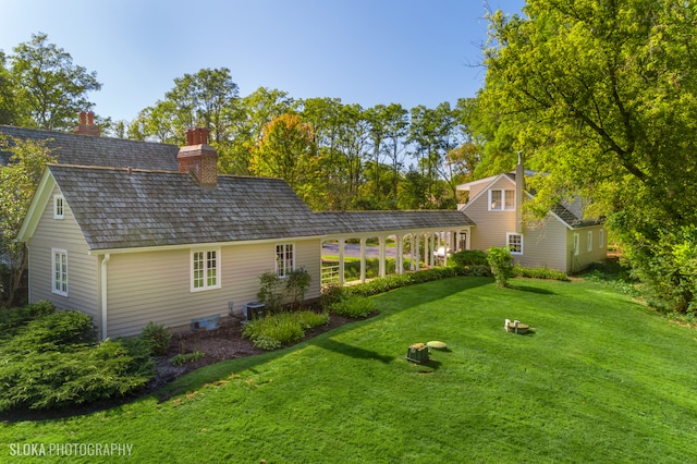 back of house featuring central AC unit and a lawn