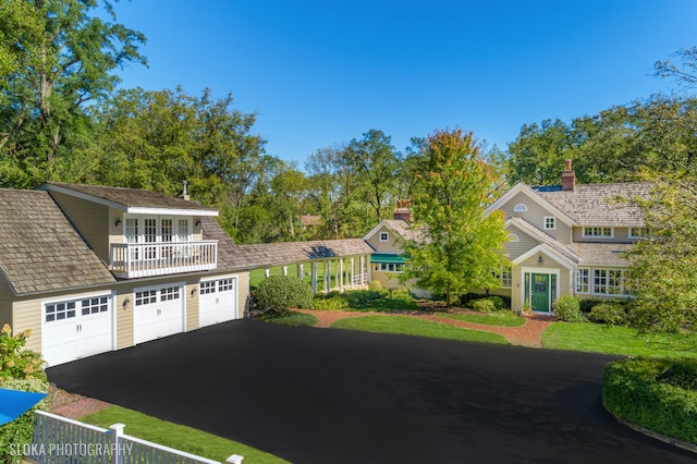 view of front of property with a balcony, a front yard, and a garage