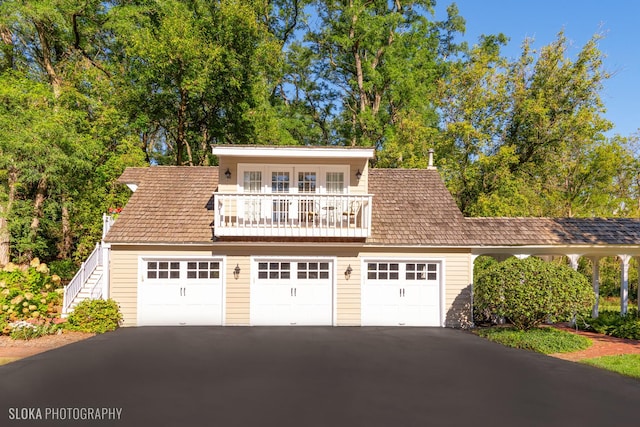 view of front of home featuring driveway, a balcony, and stairway