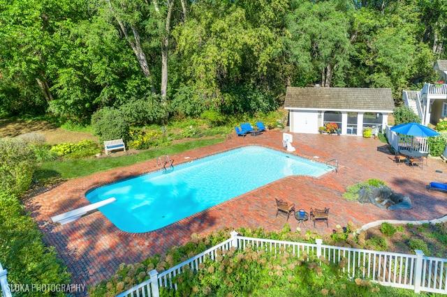 view of swimming pool featuring a diving board and an outdoor structure