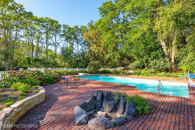 pool with fence, a diving board, and a patio area