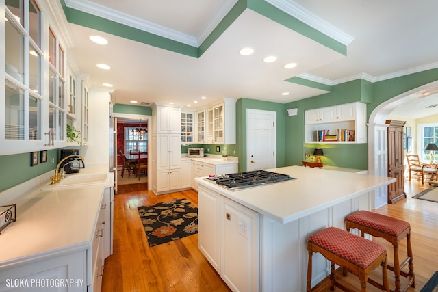 kitchen featuring stainless steel gas cooktop, a center island, white cabinets, and sink