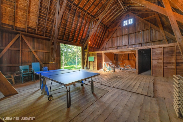 recreation room with hardwood / wood-style floors, high vaulted ceiling, beam ceiling, and wood walls