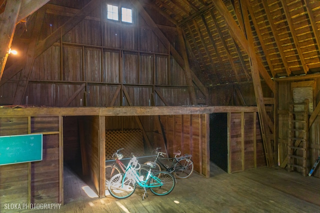 interior space with hardwood / wood-style floors, vaulted ceiling, and wooden walls