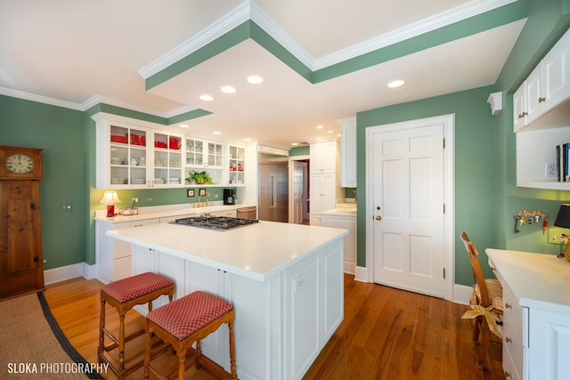 kitchen featuring a breakfast bar, a center island, crown molding, dark hardwood / wood-style floors, and white cabinetry