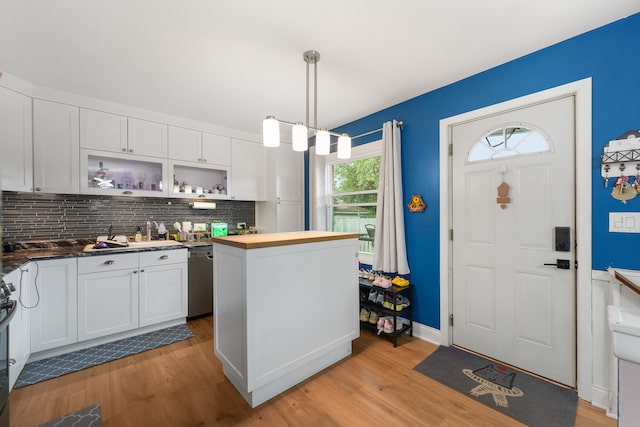 kitchen featuring white cabinets, light wood-type flooring, plenty of natural light, and decorative light fixtures