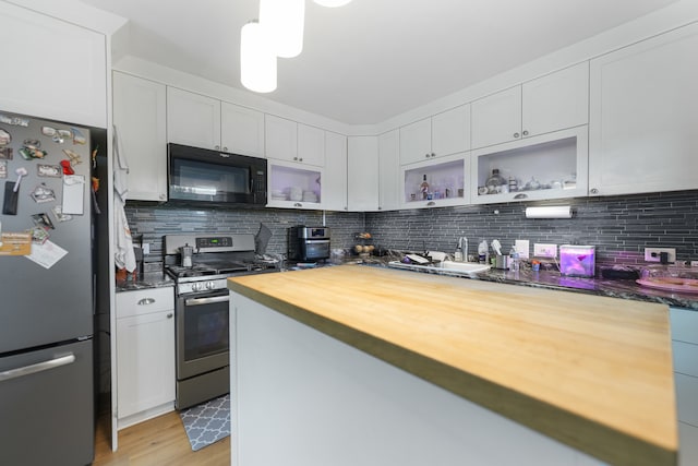 kitchen featuring wooden counters, appliances with stainless steel finishes, white cabinets, and tasteful backsplash