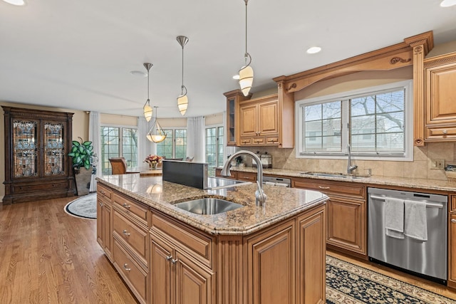 kitchen with a kitchen island with sink, sink, hanging light fixtures, and dishwasher