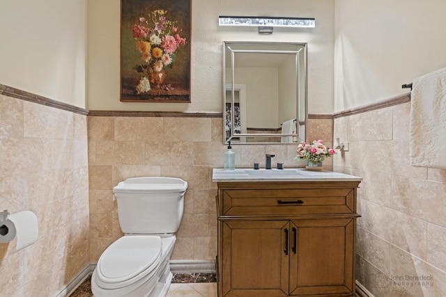 bathroom with tile patterned floors, vanity, toilet, and tile walls