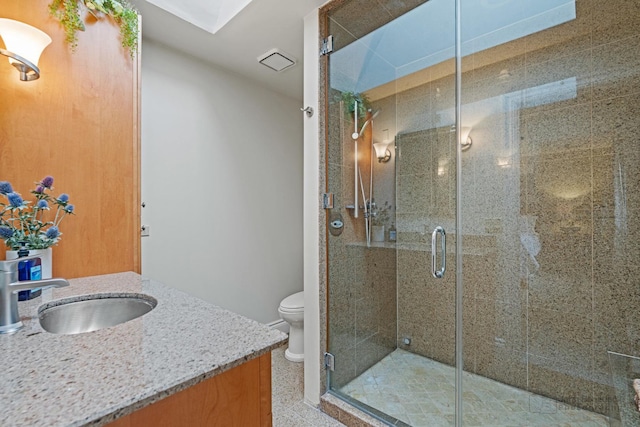 bathroom with vanity, toilet, a skylight, and a shower with door