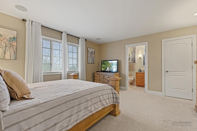 bedroom featuring connected bathroom and light carpet