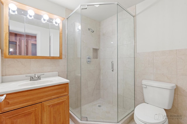 bathroom with toilet, tile walls, vanity, and a shower with shower door