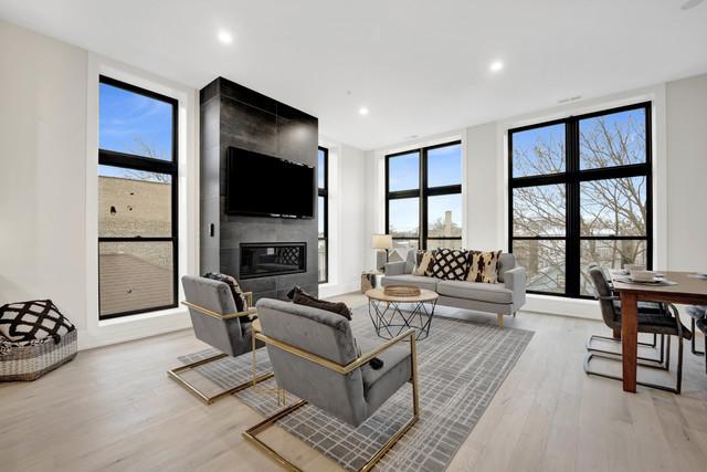 living room with expansive windows, a fireplace, and light hardwood / wood-style flooring