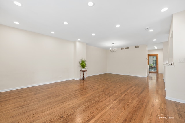 spare room featuring an inviting chandelier and light hardwood / wood-style flooring