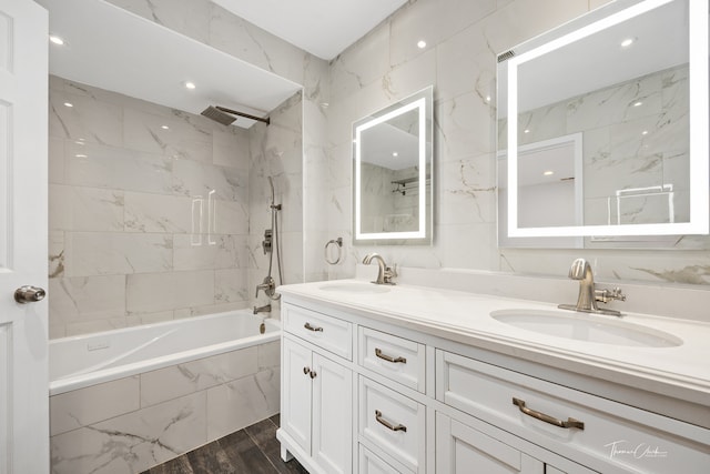 bathroom with tiled shower / bath, vanity, tile walls, and hardwood / wood-style flooring