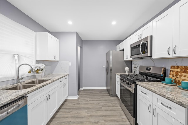 kitchen featuring white cabinets, sink, light hardwood / wood-style flooring, appliances with stainless steel finishes, and light stone counters