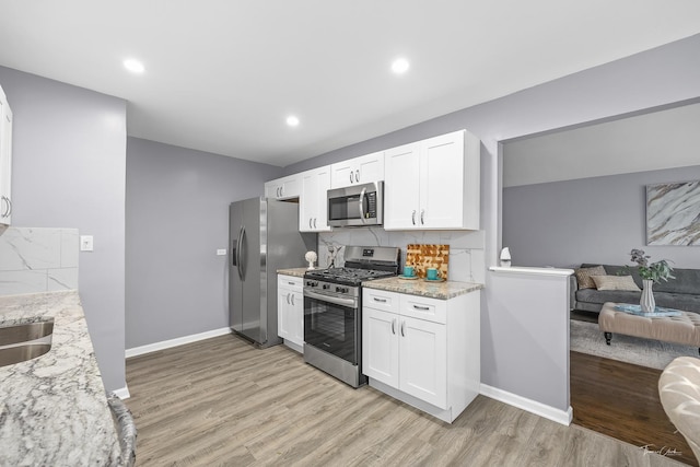 kitchen with white cabinetry, light stone countertops, and appliances with stainless steel finishes