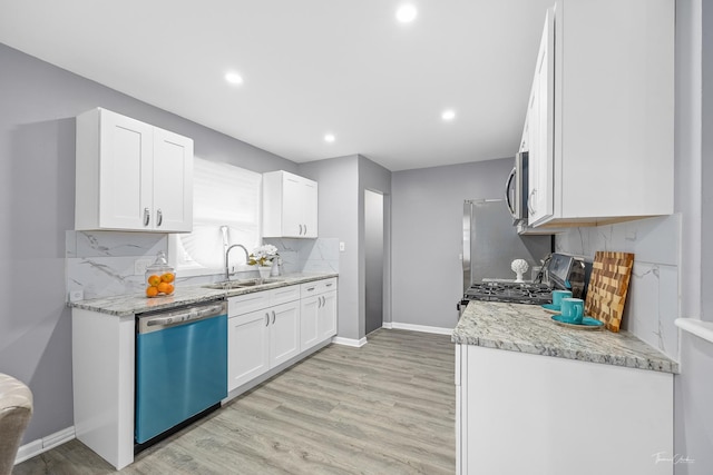 kitchen featuring light stone countertops, stainless steel appliances, sink, white cabinets, and light hardwood / wood-style floors